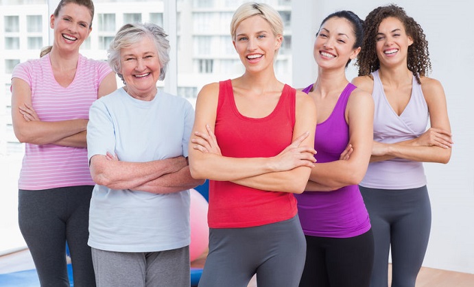portrait of confident female friends standing arms crossed in gym
